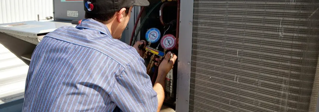 HVAC technician servicing a condenser unit in Wellesley