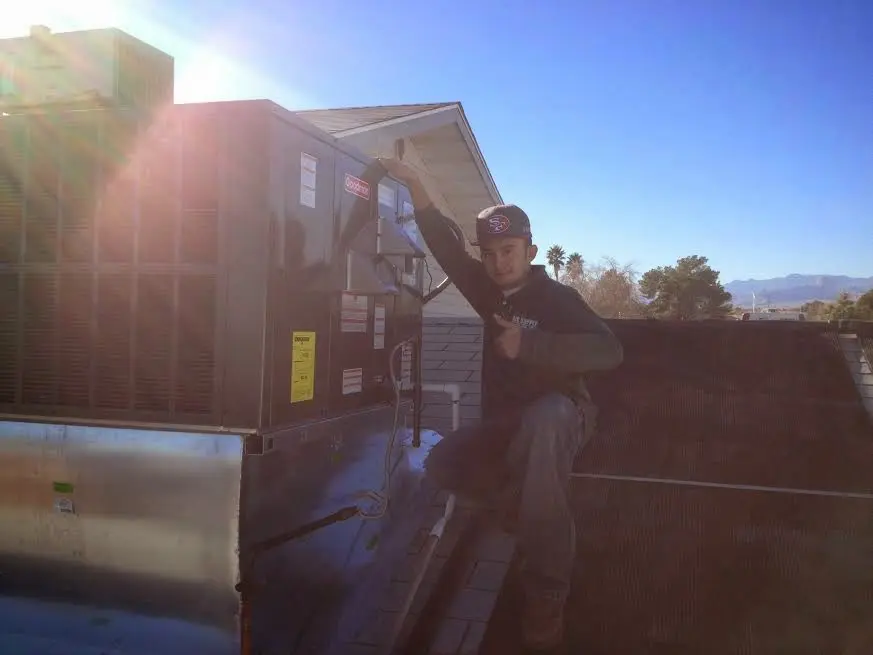 HVAC technician performing Air Duct Repair on a rooftop unit in Wellesley